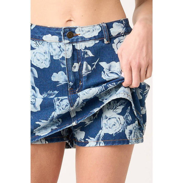 Blue floral denim shorts being held up against a white background