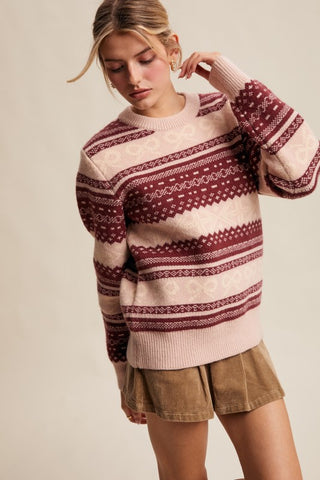 Woman wearing a patterned sweater and shorts on a plain background
