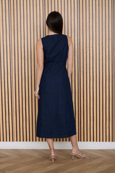 Woman wearing a navy denim dress standing against a striped wall.
