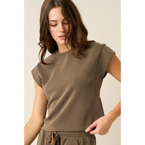 A woman wearing a short-sleeve crewneck top in a solid taupe-brown color, paired with matching drawstring pants, set against a plain beige background.
