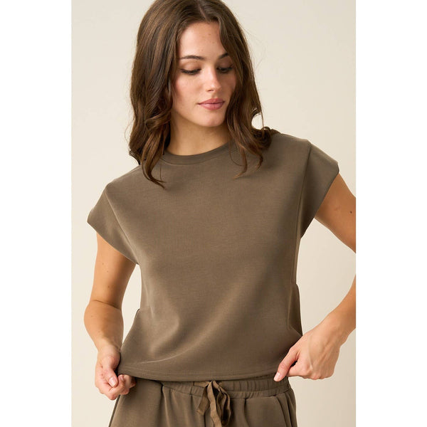 A woman wearing a short-sleeve crewneck t-shirt in a solid taupe-brown color, paired with matching drawstring pants, set against a plain beige background.