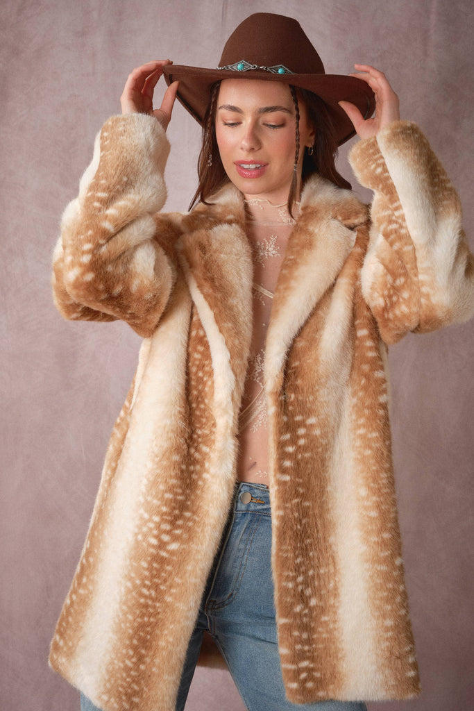 Woman wearing a fur coat and hat against a plain background