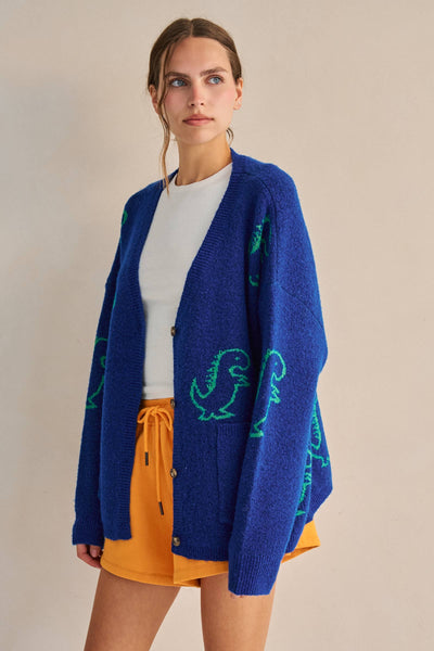 Woman wearing a blue cardigan with green dinosaur patterns on a beige background