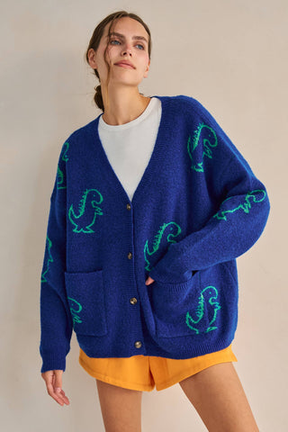 Woman wearing a blue cardigan with green patterns on a beige background