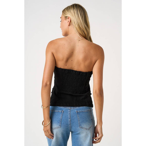 Woman wearing a black strapless top and blue jeans on a white background