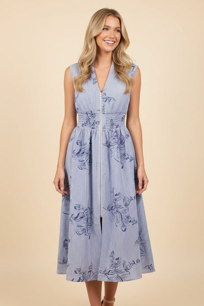 Woman wearing a blue floral pinstripe midi dress with a sleeveless design, smocked waist, front zipper, pockets, and A-line skirt