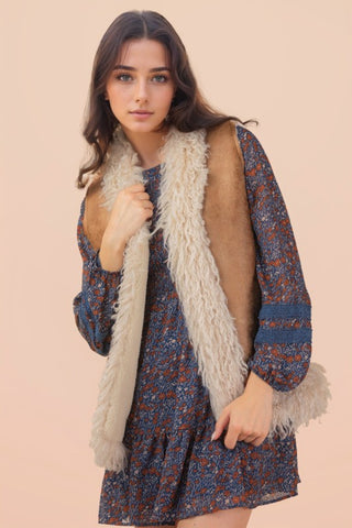Woman wearing a floral dress with a fur vest against a beige background