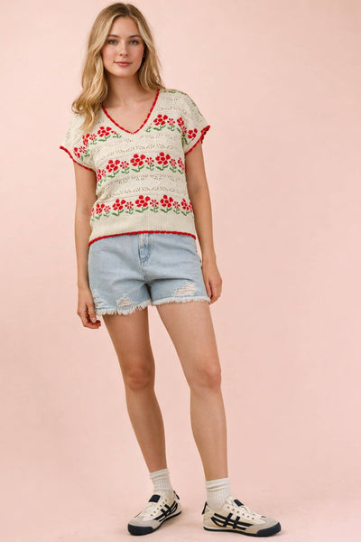 Woman wearing a floral top and denim shorts on a pink background