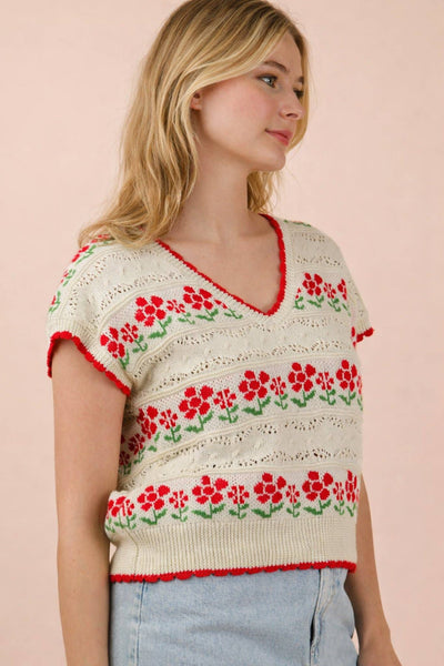Woman wearing a floral-patterned sweater against a pink background
