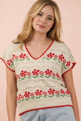 Woman wearing a floral-patterned sweater against a pink background