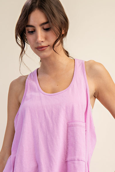A woman wearing a light pink sleeveless tank top with a chest pocket, shown from the chest up against a plain beige background.