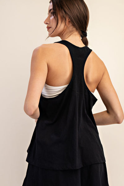 Woman wearing a black sleeveless top over a white shirt on a beige background