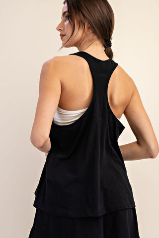 Woman wearing a black sleeveless top over a white shirt on a beige background
