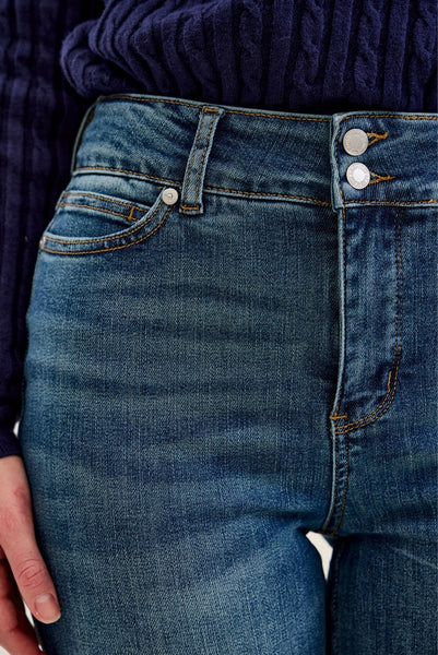 Close-up of blue jeans with a focus on the waistband and buttons.