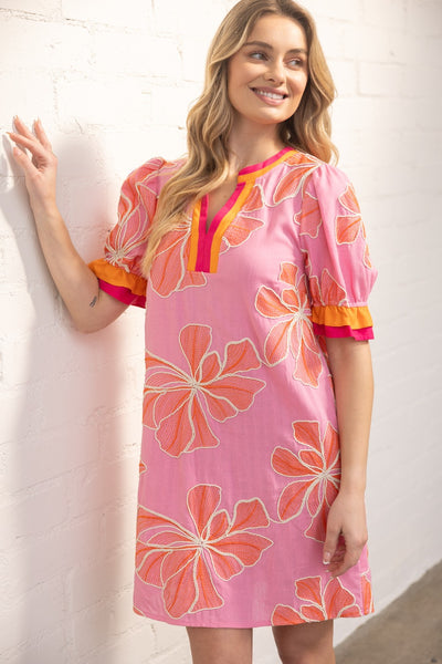 Woman wearing a pink floral dress with orange flowers against a white background