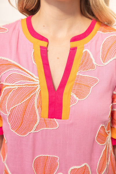Close-up of a pink garment with butterfly patterns and yellow accents.