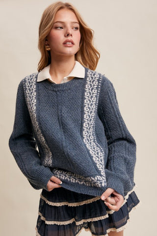 Woman wearing a blue sweater with white lace details on a beige background