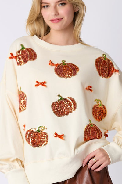 Woman wearing a cream sweater with pumpkin patterns on a white background