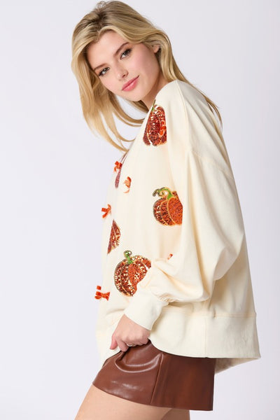Woman wearing a cream-colored sweater with pumpkin patterns and a brown leather skirt on a white background