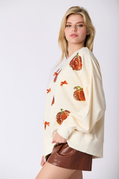 Woman wearing a cream-colored sweatshirt with strawberry patterns on a white background