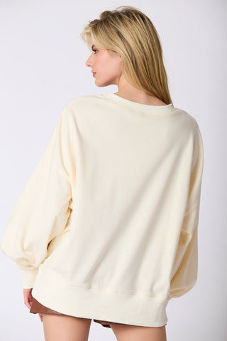 Woman wearing a cream-colored sweater against a plain background