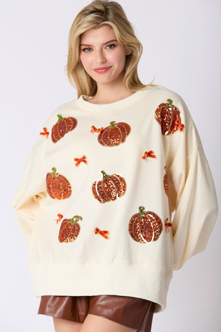 Woman wearing a cream sweater with pumpkin patterns on a white background