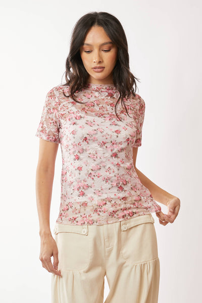 Woman wearing a floral top and beige pants on a white background
