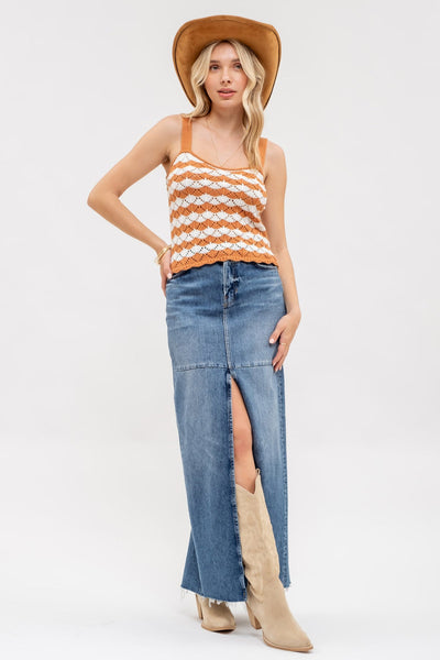 Woman wearing a striped tank top, denim skirt, and cowboy boots on a white background