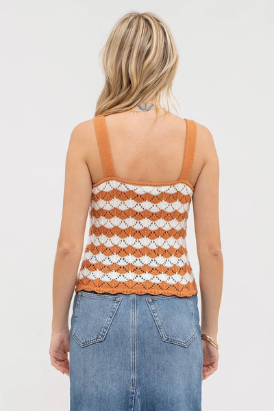 Woman wearing a striped tank top and jeans on a plain background