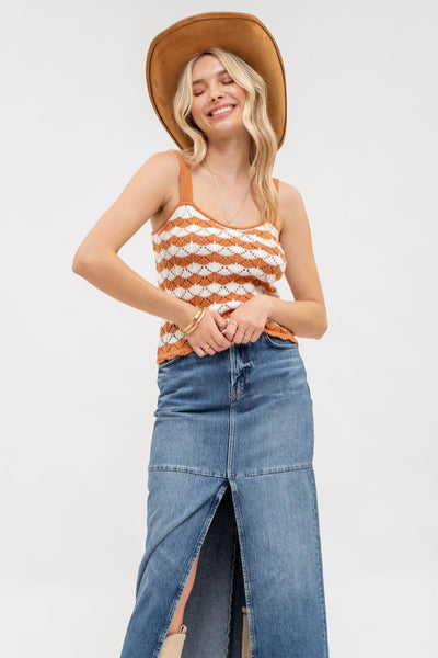 Woman wearing a striped tank top, denim skirt, and brown hat on a white background
