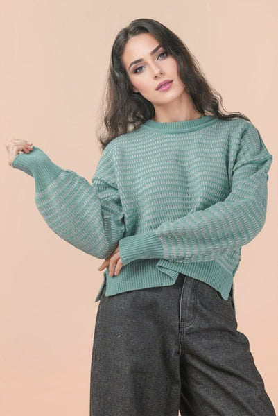 Woman wearing a teal sweater against a beige background