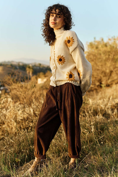 Woman wearing a cream sweater with sunflower patterns in a field