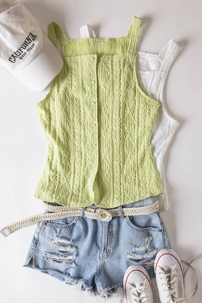 Green knitted tank top, denim shorts, white sneakers, and a white cap on a light gray background.