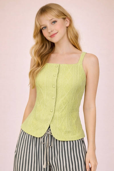 Woman wearing a light green sleeveless top with buttons on a pink background