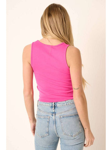 A woman shown from the back wearing a bright pink sleeveless tank top and light blue jeans, standing against a plain light beige background.