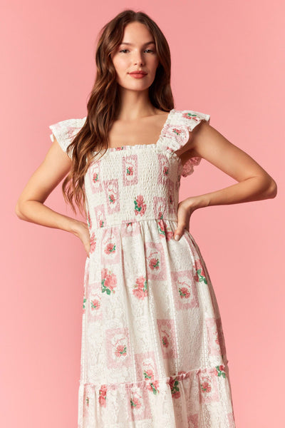 Woman wearing a vintage floral smocked midi dress with a square neckline, ruffle sleeves, and a flowy tiered skirt.