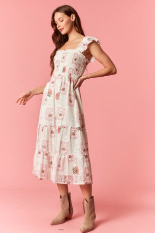 Woman wearing a vintage floral smocked midi dress with a square neckline, ruffle sleeves, and a flowy tiered skirt.