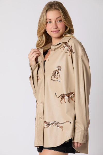 Woman wearing a beige jacket with embroidered leopards on a white background