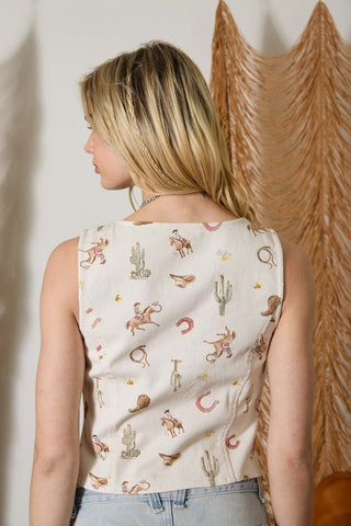 Woman wearing a sleeveless top with a cactus pattern against a textured wall.