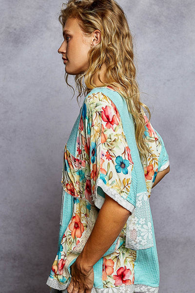 Woman wearing a colorful floral kimono top against a gray background
