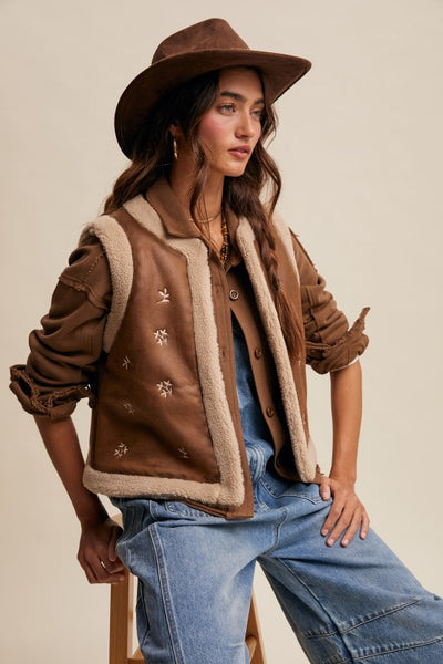 Woman wearing a brown shearling jacket and hat with a neutral background